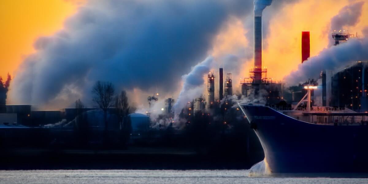 ship in water with smoke stacks in the background