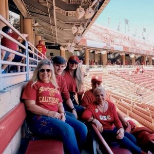 Square image of Trojan family at a football game sitting in the bleachers