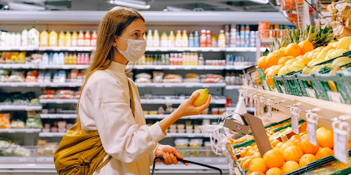 woman shopping in a grocery store with a mask on 
