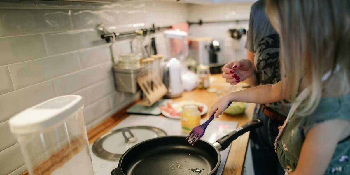 Girl cooking on a nonstick pan with family.
