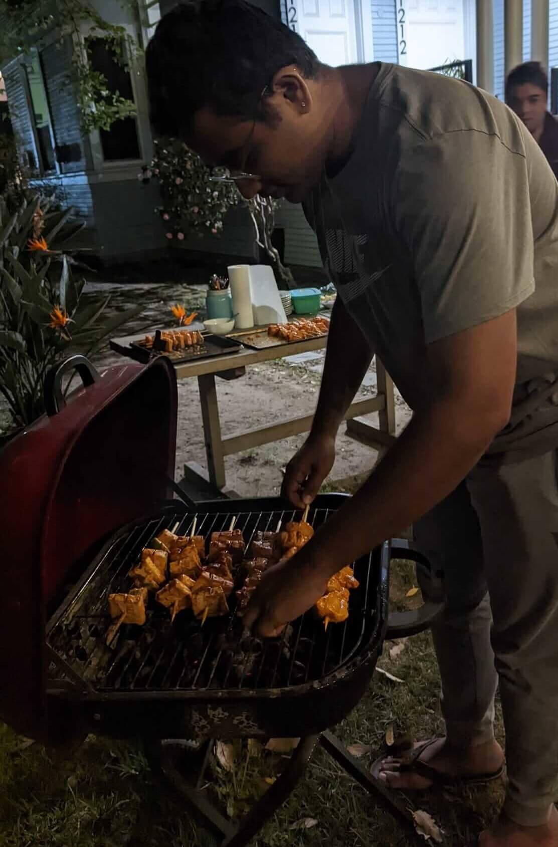 student cooking food on grill at night