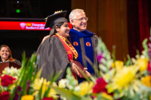 Akshita Swaminathan and Dean Yannis Yortsos at the 2023 commencement ceremony at The Galen Center