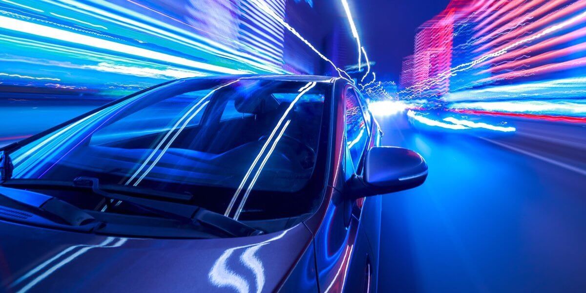 A futuristic car driving through a tunnel of lights