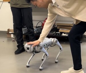 Dynamic Robotics and Control Lab Researcher Junheng Li tapping on the robot dog