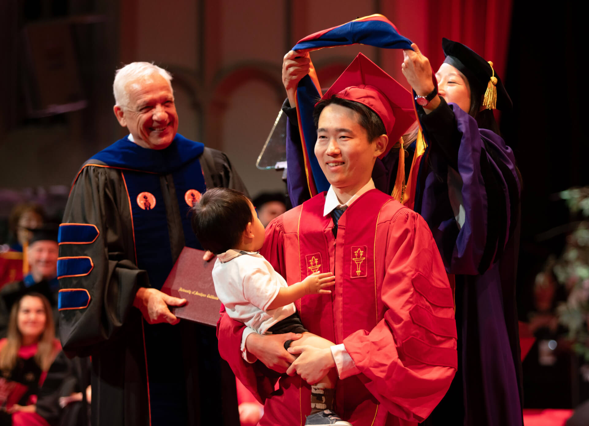 Yi Huang receives his hood from Ph.D. advisor Eun Ji Chung as Dean Yortsos looks on. 