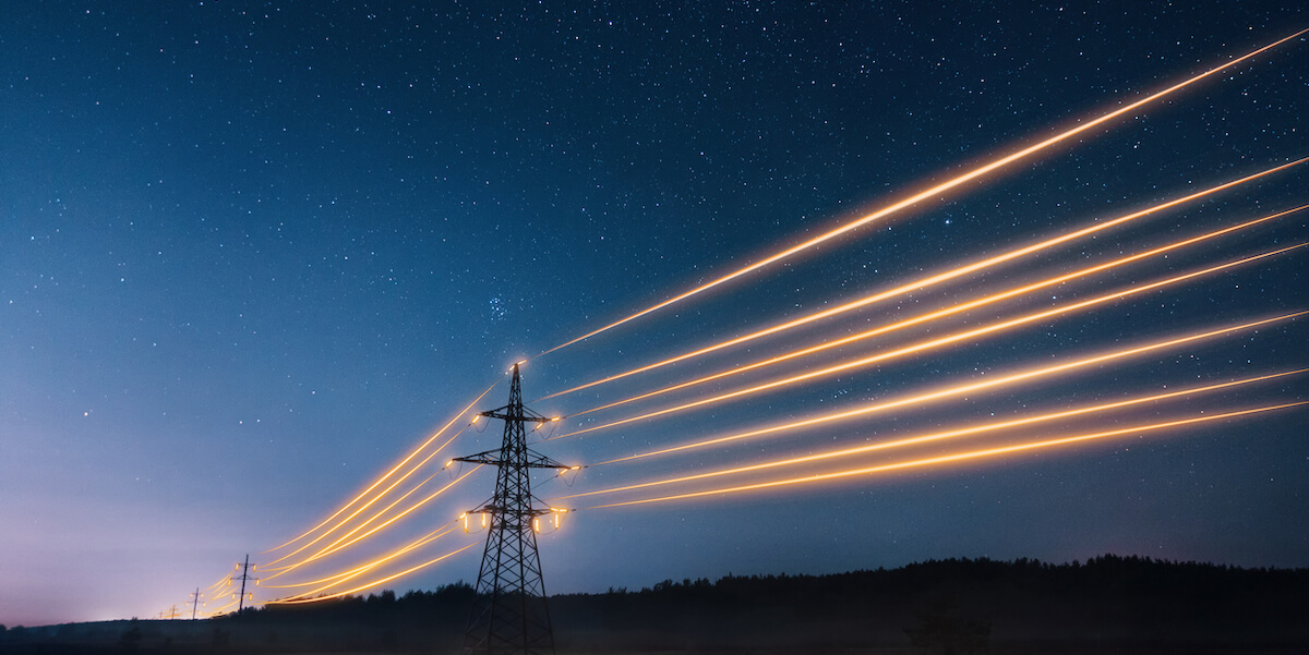 Electrical towers light up with against the backdrop a starry night in the countryside.