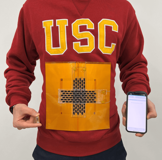 A person wearing a USC sweatshirt with a large patch with a magnetic coil in the shape of a cross.