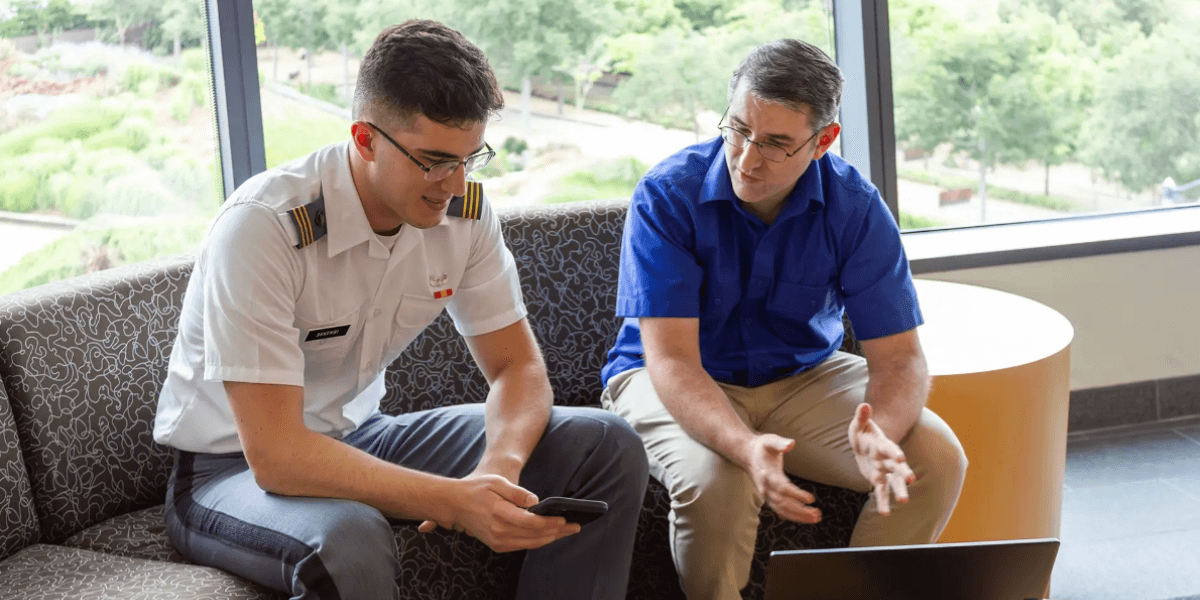 Dr. Ben Nye sits on a couch and has a discussion with the person holding a phone and sitting next to him.