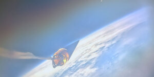 Photo from space. The nose cone of USCRPL's rocket points towards the moon, across Earth's horizon