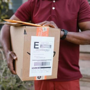 A delivery driver carries a box. Image/Pexels.