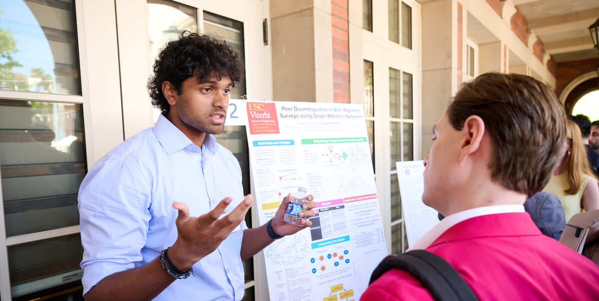 student in front of a poster talking to another person viewing his poster