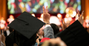 the backs of students' commencement caps as they give the USC "fight on" sign while looking at the stage