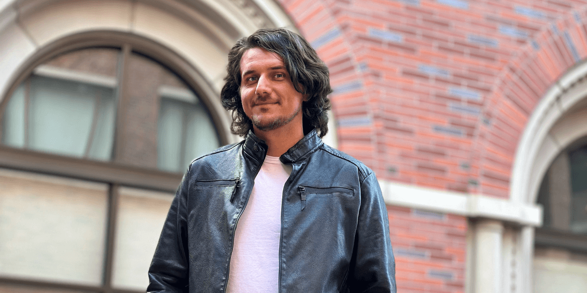 Man in jacket in front of red brick building.
