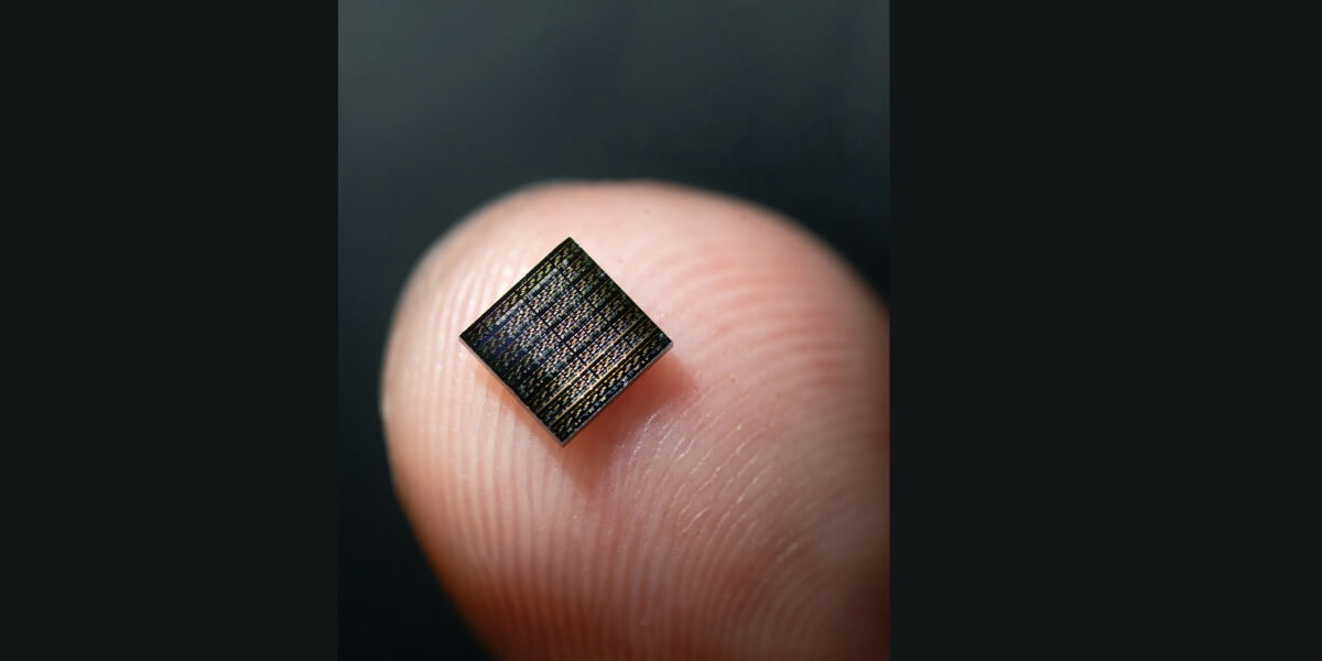 the chip of an array of these integrated artificial neurons sits on a top of a finger tip, showing its small size