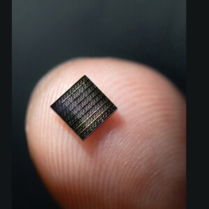 square image of a neuromorphic chip balancing on a finger tip, it is smaller than the finger tip